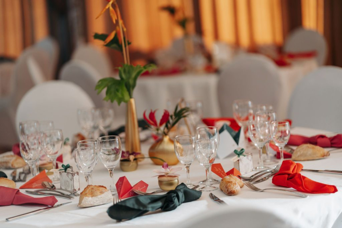 Table de mariage aux serviettes rouges et vertes Table de mariage nappée de blanc avec serviettes rouges et vertes, verres à pied et centre de table doré