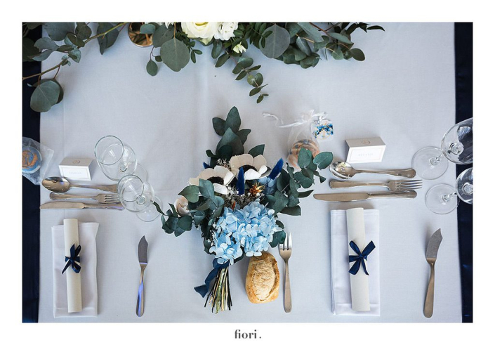 Assiette de mariage hortensia bleu et eucalyptus Assiette de mariage vue du dessus : bouquet d'hortensia bleu et d'eucalyptus, serviettes roulées nouées d'un ruban bleu marine